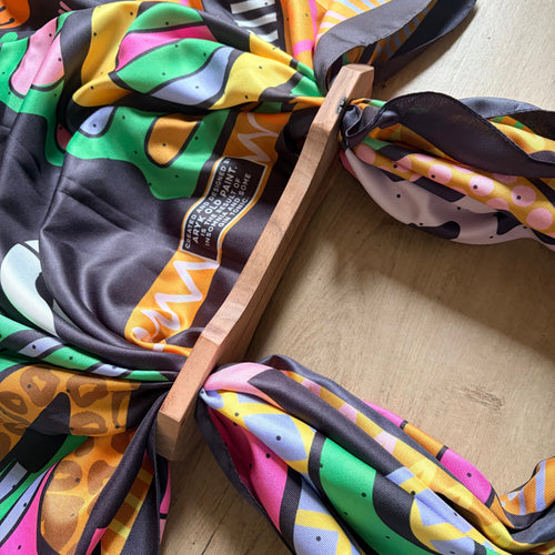 Foulard "It's Ok" ARYK OLD PAINT annodato ai manici in legno artigianali – illustrazione astratta multicolore su fondo grigio scuro, vista dall'alto