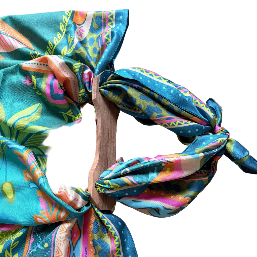 Dettaglio del foulard "Paradise" ARYK OLD PAINT annodato ai manici in legno – illustrazione originale con motivi tropicali multicolore su fondo turchese
