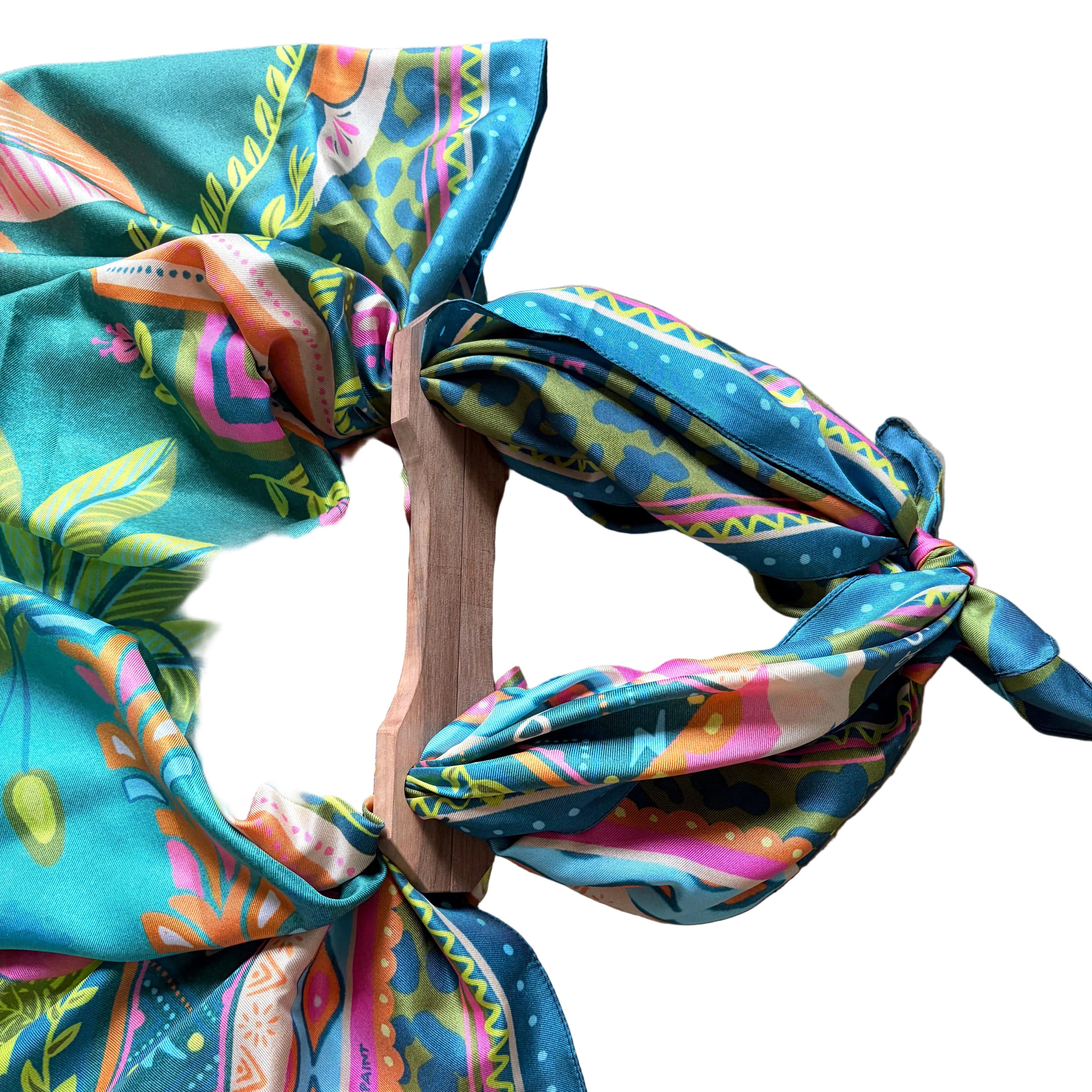 Dettaglio del foulard "Paradise" ARYK OLD PAINT annodato ai manici in legno – illustrazione originale con motivi tropicali multicolore su fondo turchese
