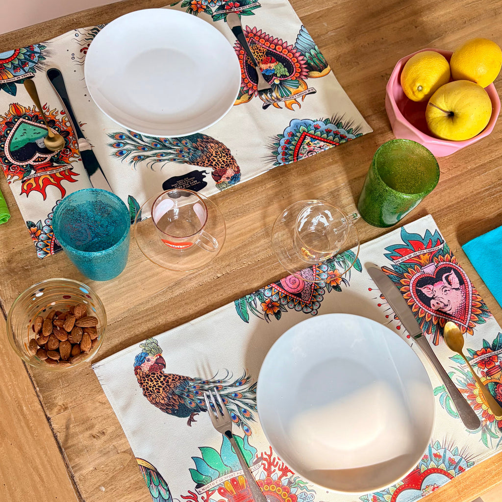 Set da 2 tovagliette "La Solita Zuppa" ARYK OLD PAINT su tavolo in legno con posate – illustrazione old school con cuori sacri, maiale e scimmia leopardata, sfondo bianco
